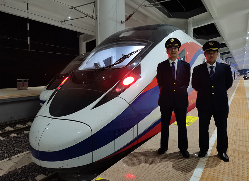 劉銀能（右一）與中國師父鄔俊鴻在動車組前合影。受訪者供圖